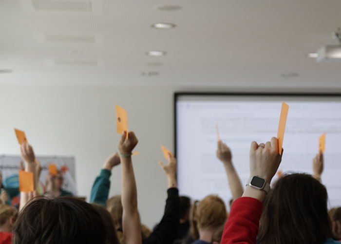 Hände recken Karten zur Abstimmung in die Luft